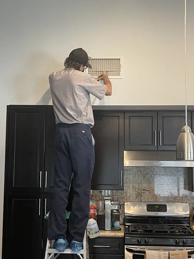 Technician inspecting an air vent during HVAC service in Wilton Manors